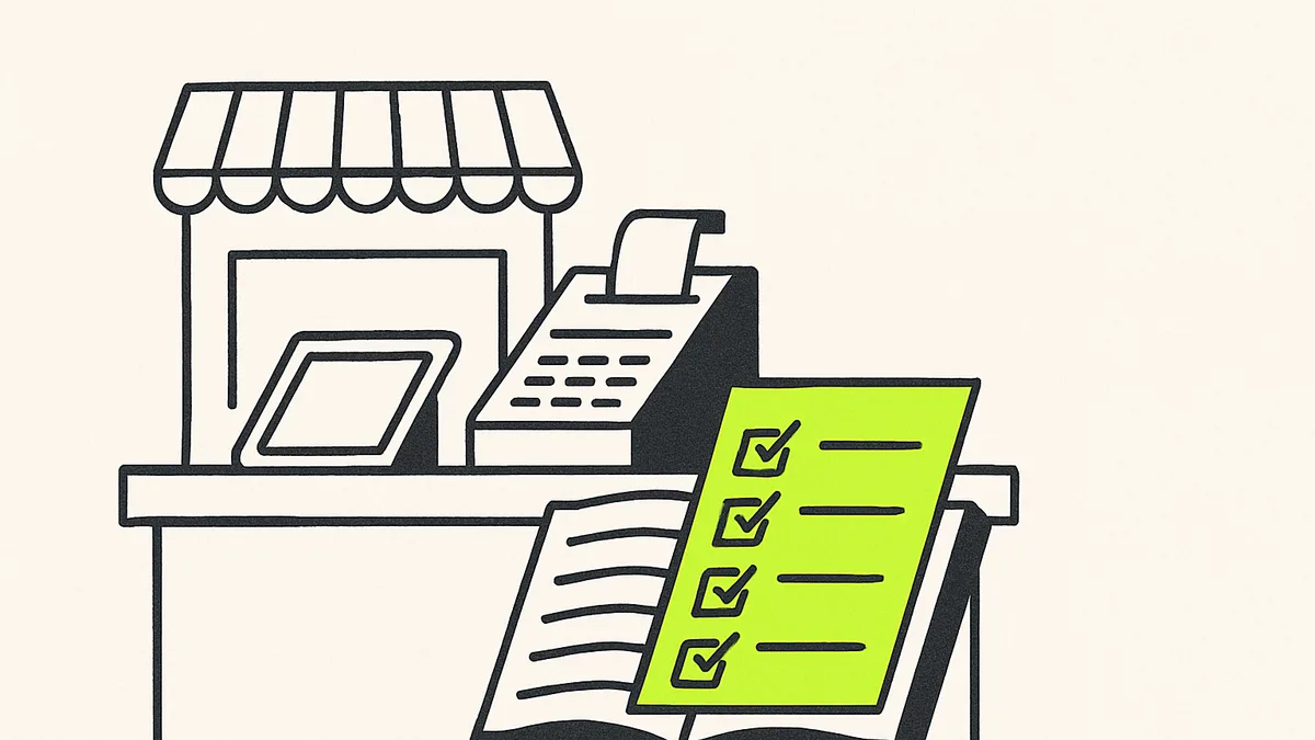 A small shop counter with a tablet beside the register and a paper ledger half-covered by a green checklist